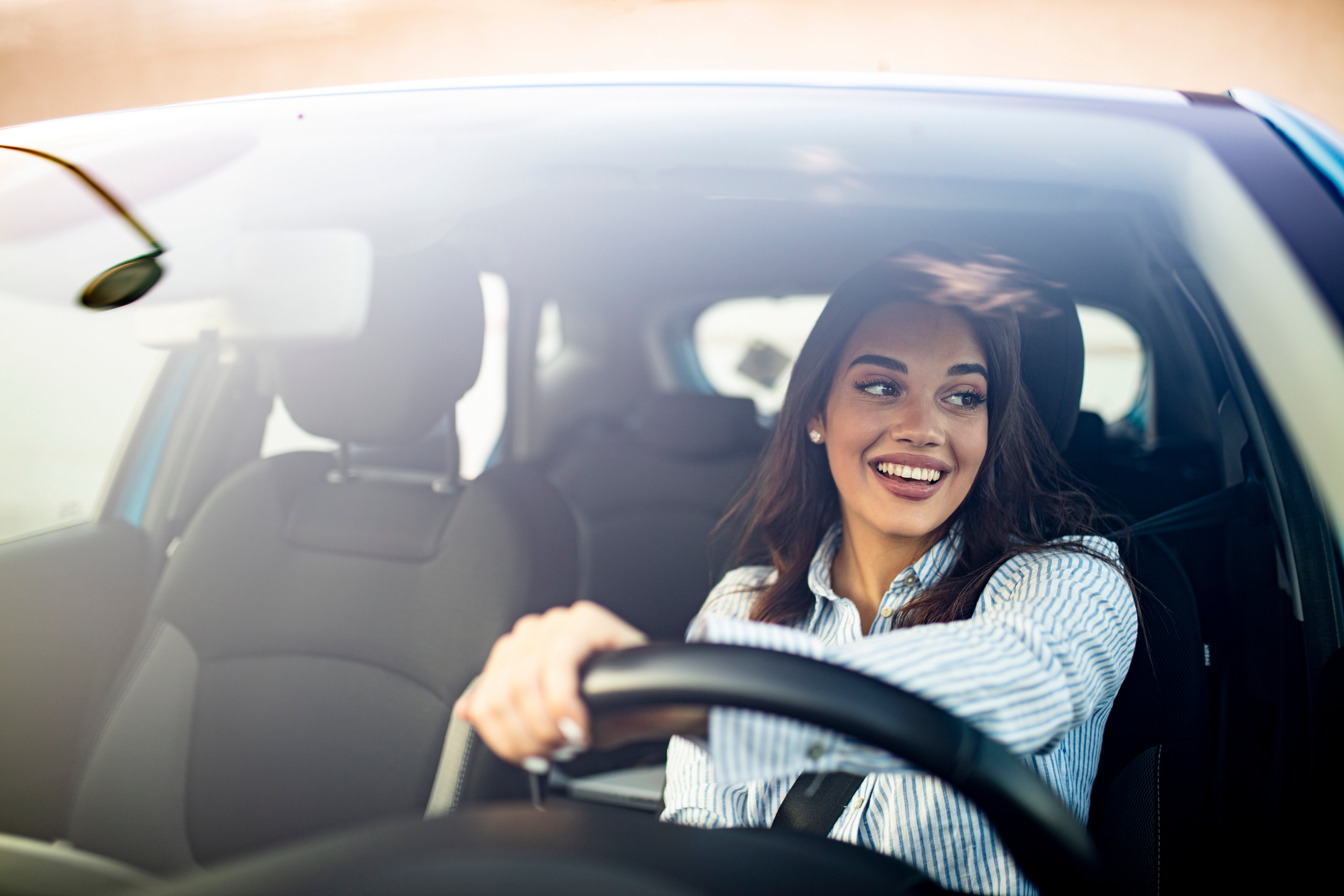 egy nő mosolyog egy használt autó volánja mögött